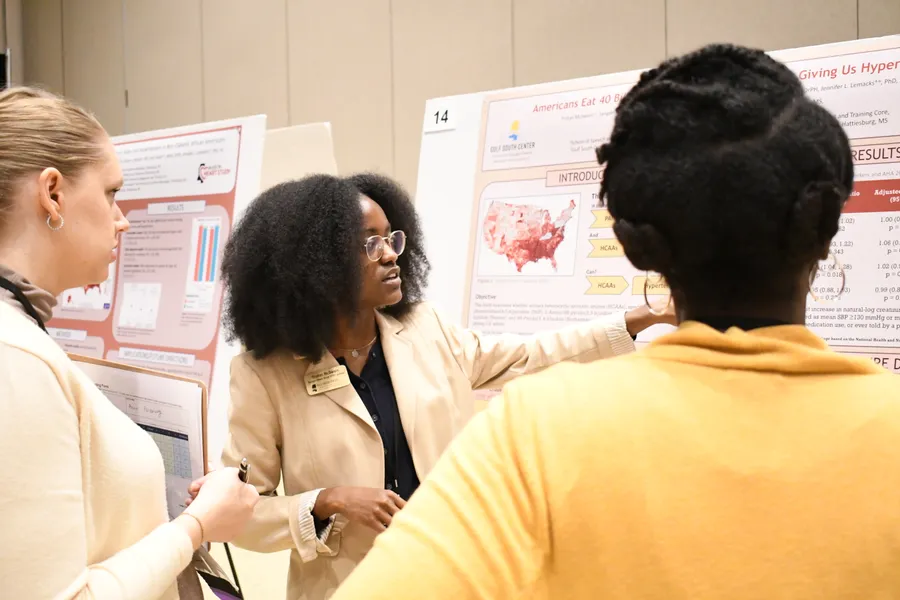 A scholar discussing her research poster with an attendee